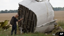 Малазийский следователь делает фотографии обломков малазийского авиалайнера рейса МН-17 на месте падения самолета в Украине. 22 июля 2014 г.