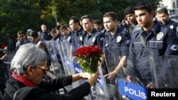 A demonstrator holds flowers before a police barricade during a commemoration for the victims of Saturday's bomb blasts in the Turkish capital, in Ankara, Turkey, October 11, 2015.